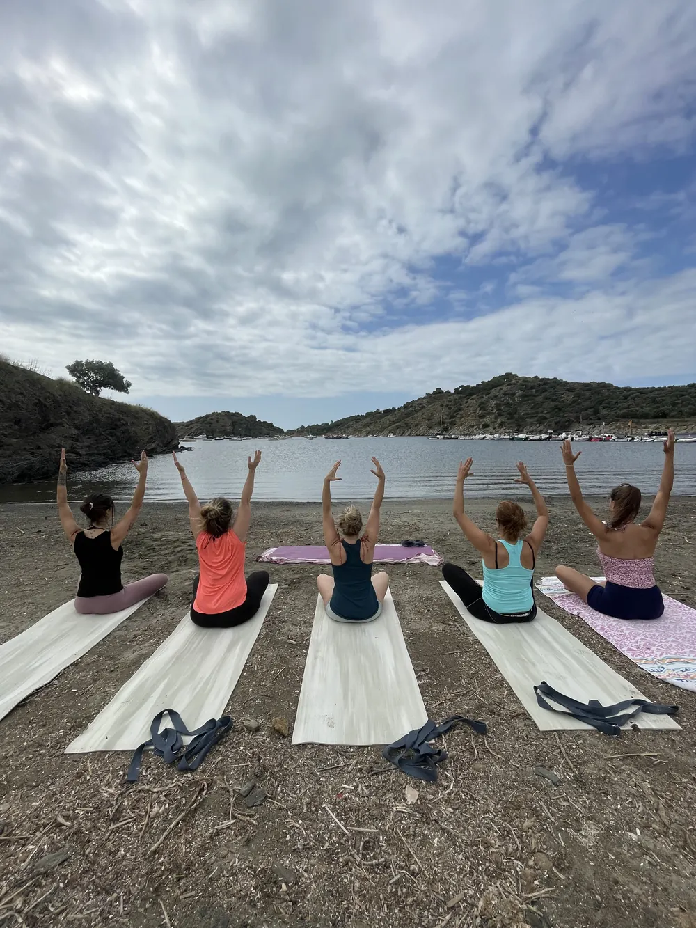 Grupo practicando yoga al aire libre junto al mar en la Costa Brava